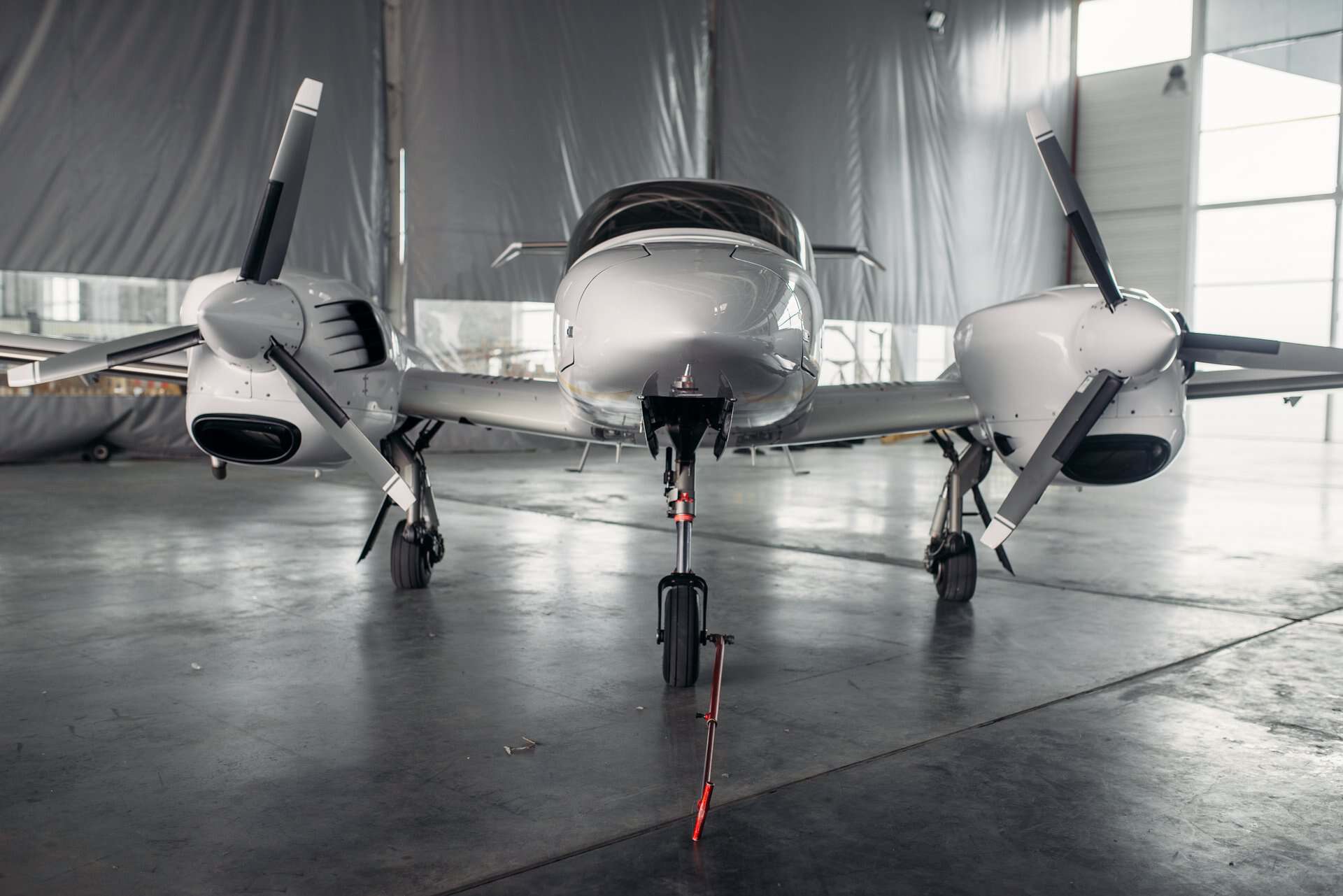Modern twin-engine aircraft inside a hangar for maintenance or inspection.
