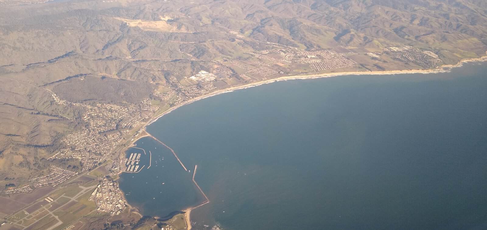 Half Moon Bay Airport aerial view over El Granada, California - the coastal geography that traps marine layer fog against the runway