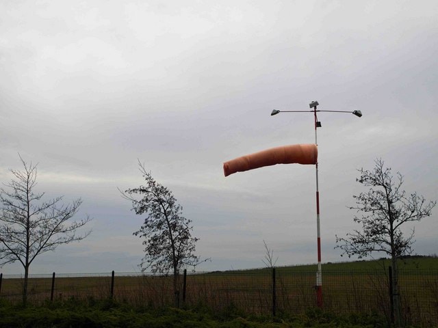 Small airport windsock with cloudy sky — a second wind shear recognition ground-truth check for GA pilots.